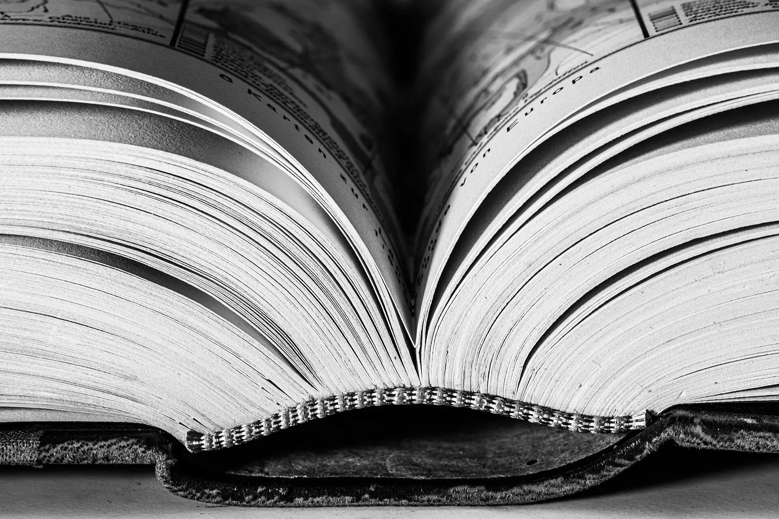 Livro aberto, com centenas de páginas em leque, fotografado em preto e branco