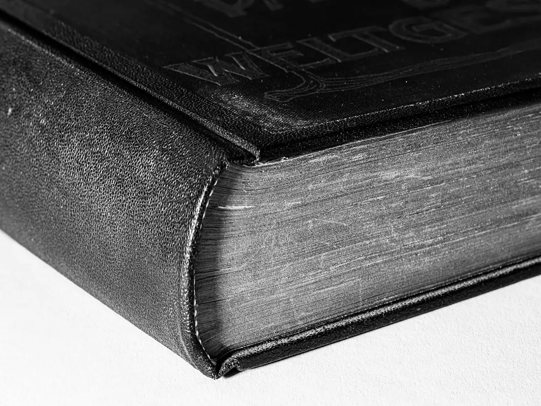 Canto de um livro fechado de capa escura, em preto e branco
